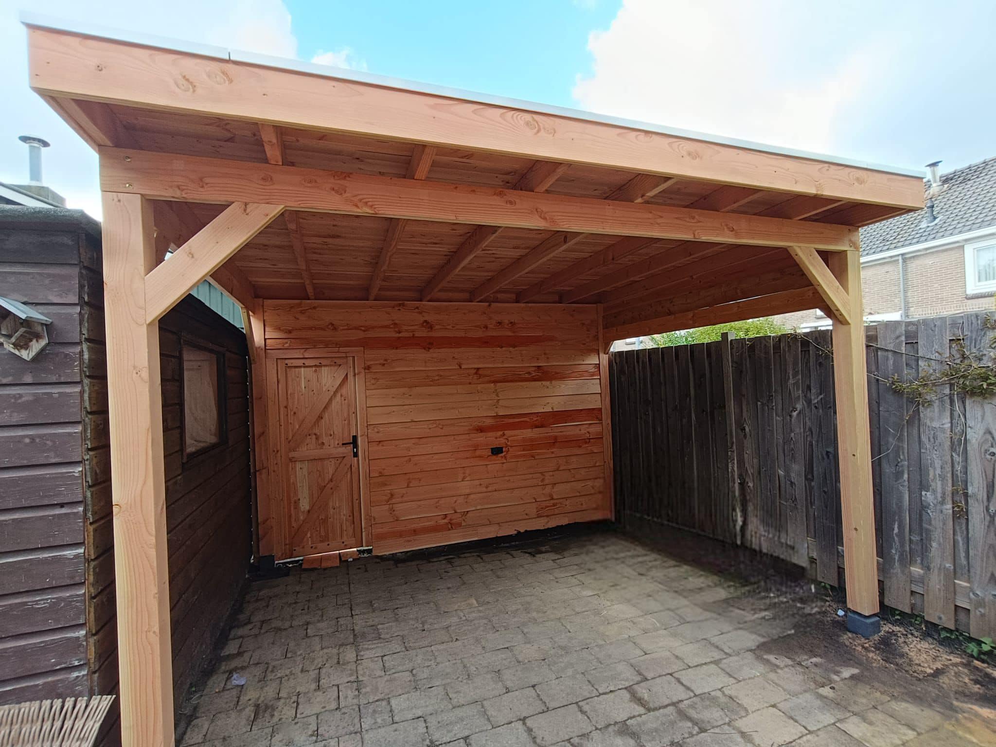 Houten overkapping: Een overkapping van hout, aansluitend op de schuur.